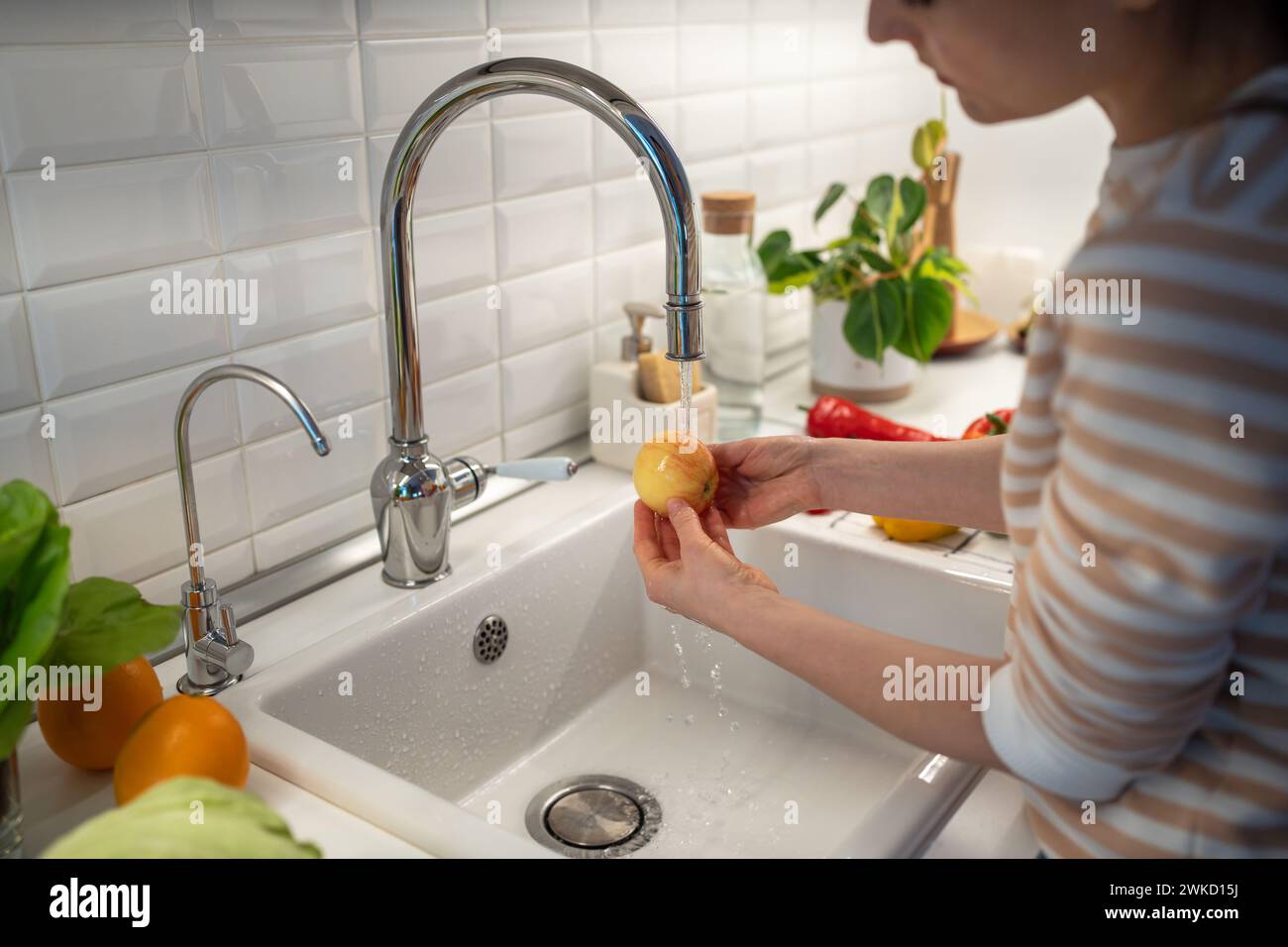 Woman hands washing apple in tap water to clean from wax paraffin protecting from quick decay Stock Photo
