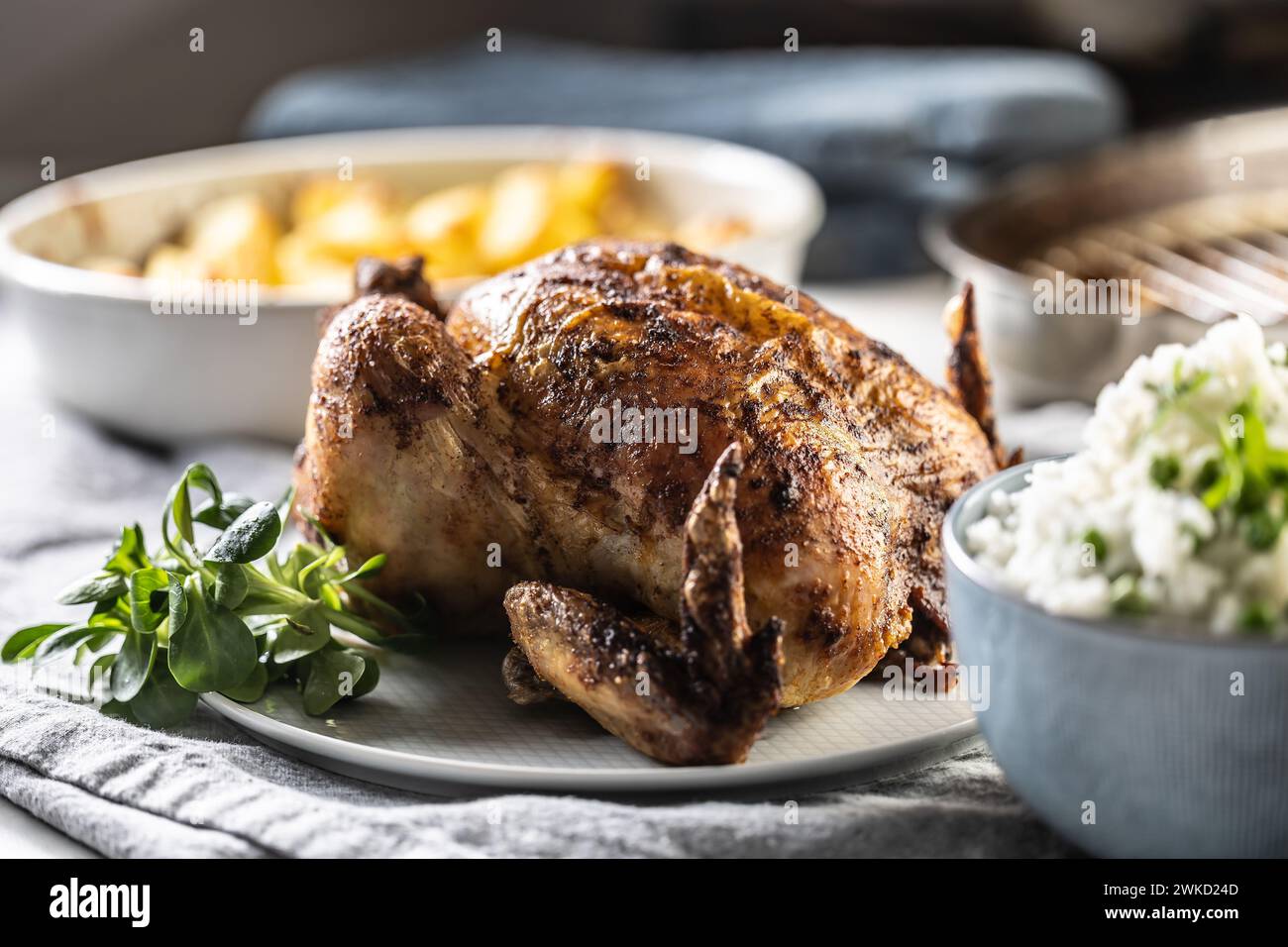 A whole roasted chicken on the table together with jasmine rice and baked potatoes. Stock Photo
