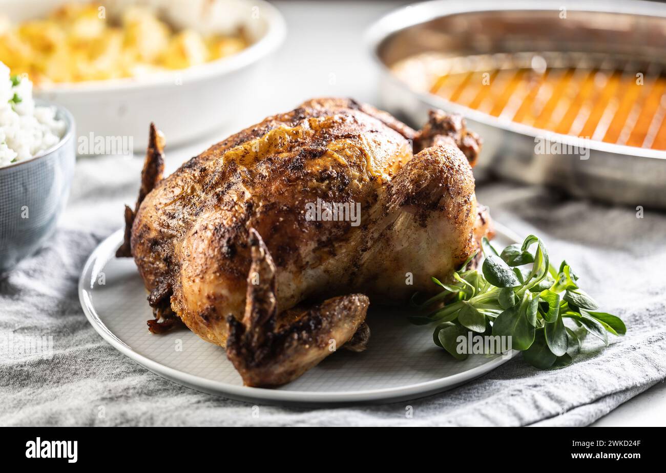 A whole roasted chicken on the table together with jasmine rice and baked potatoes. Stock Photo