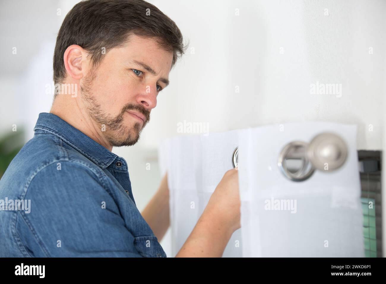 man fixing curtain on to rail Stock Photo