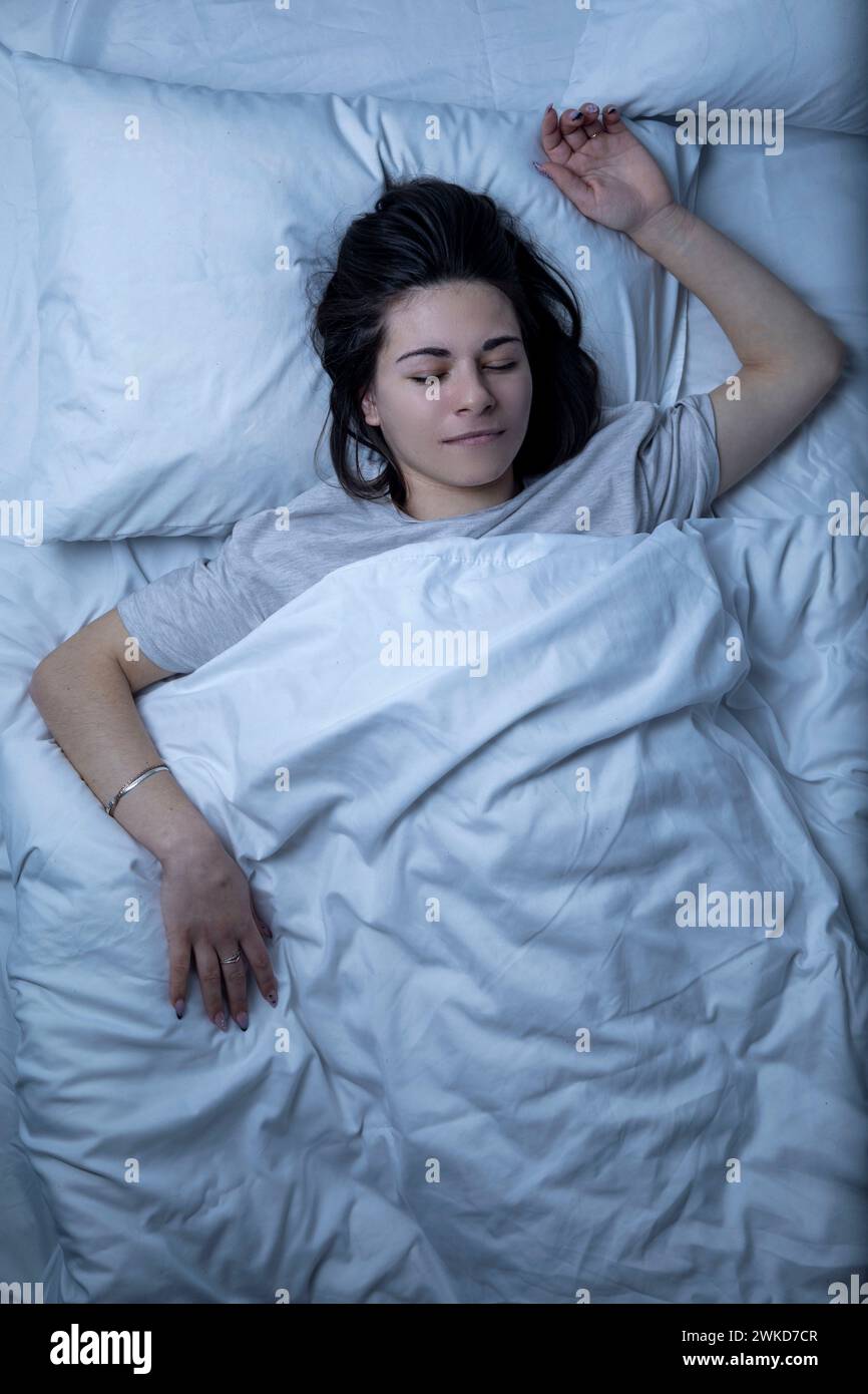 A beautiful girl is sleeping in a bed with a white sheet Stock Photo ...