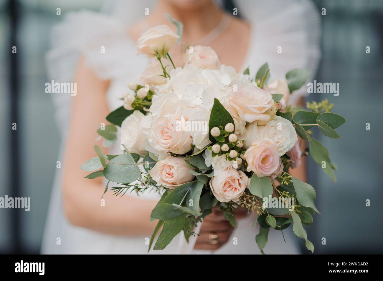 A beautiful wedding bouquet in the hands of the bride. A bouquet with white roses in the hands of the bride Stock Photo
