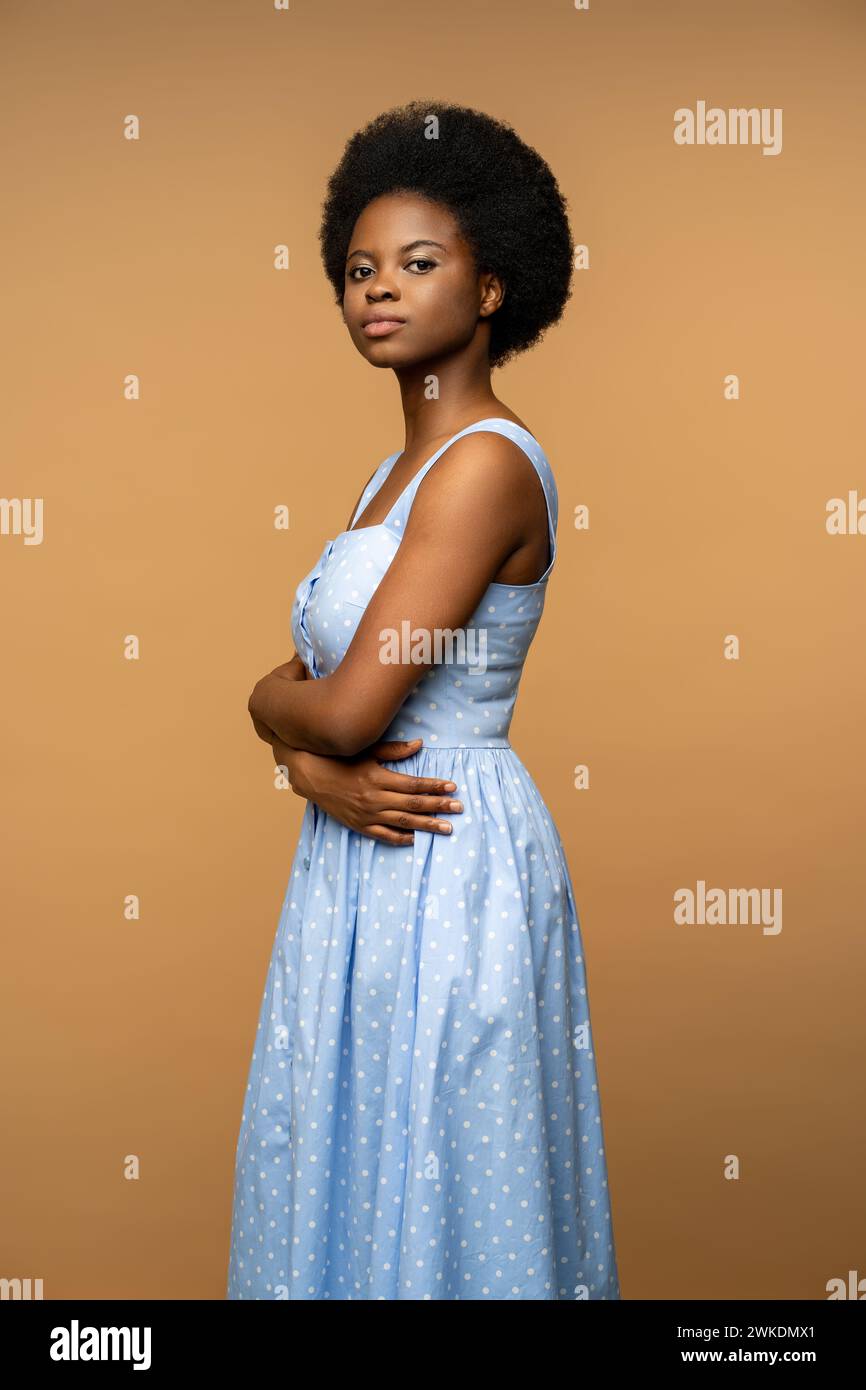 Studio portrait black young woman in blue dress with confident glance arms crossed looking at camera Stock Photo