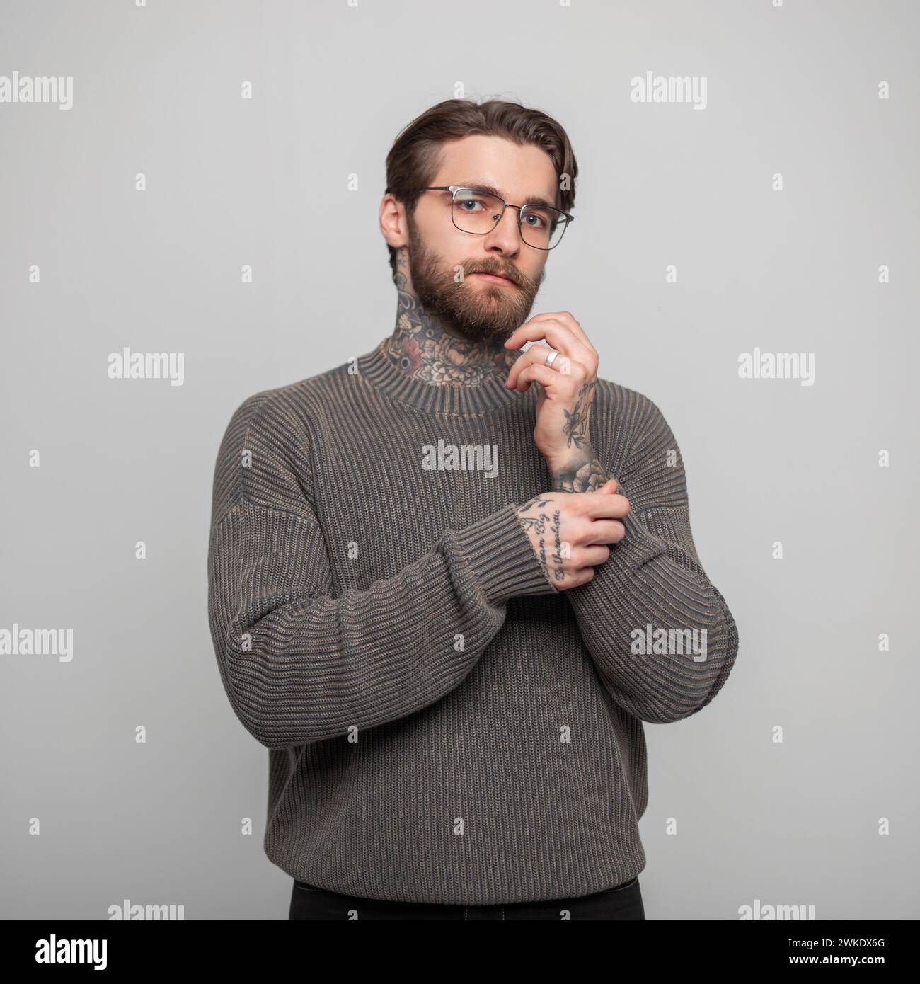 Beautiful Fashion Male Studio Portrait Of Handsome Business Man With Hairstyle And Tattoos With Sunglasses In Vintage Stylish Knitted Gray Sweater On Stock Photo