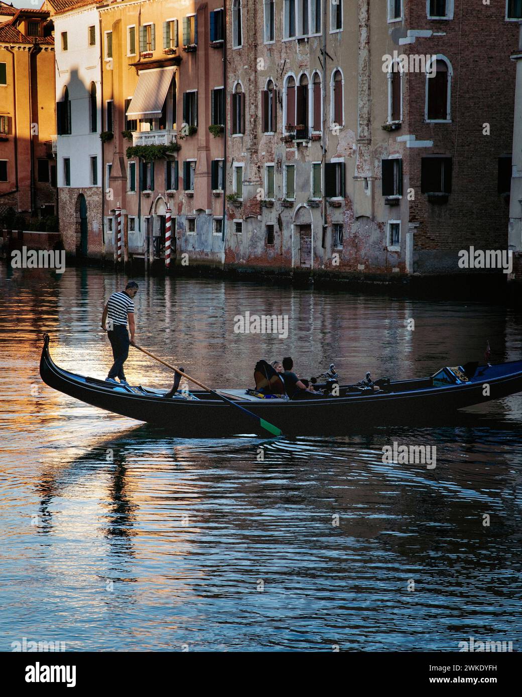 A couple enjoys a gondola ride on one of many small side canals in historic Venice, Italy. Stock Photo
