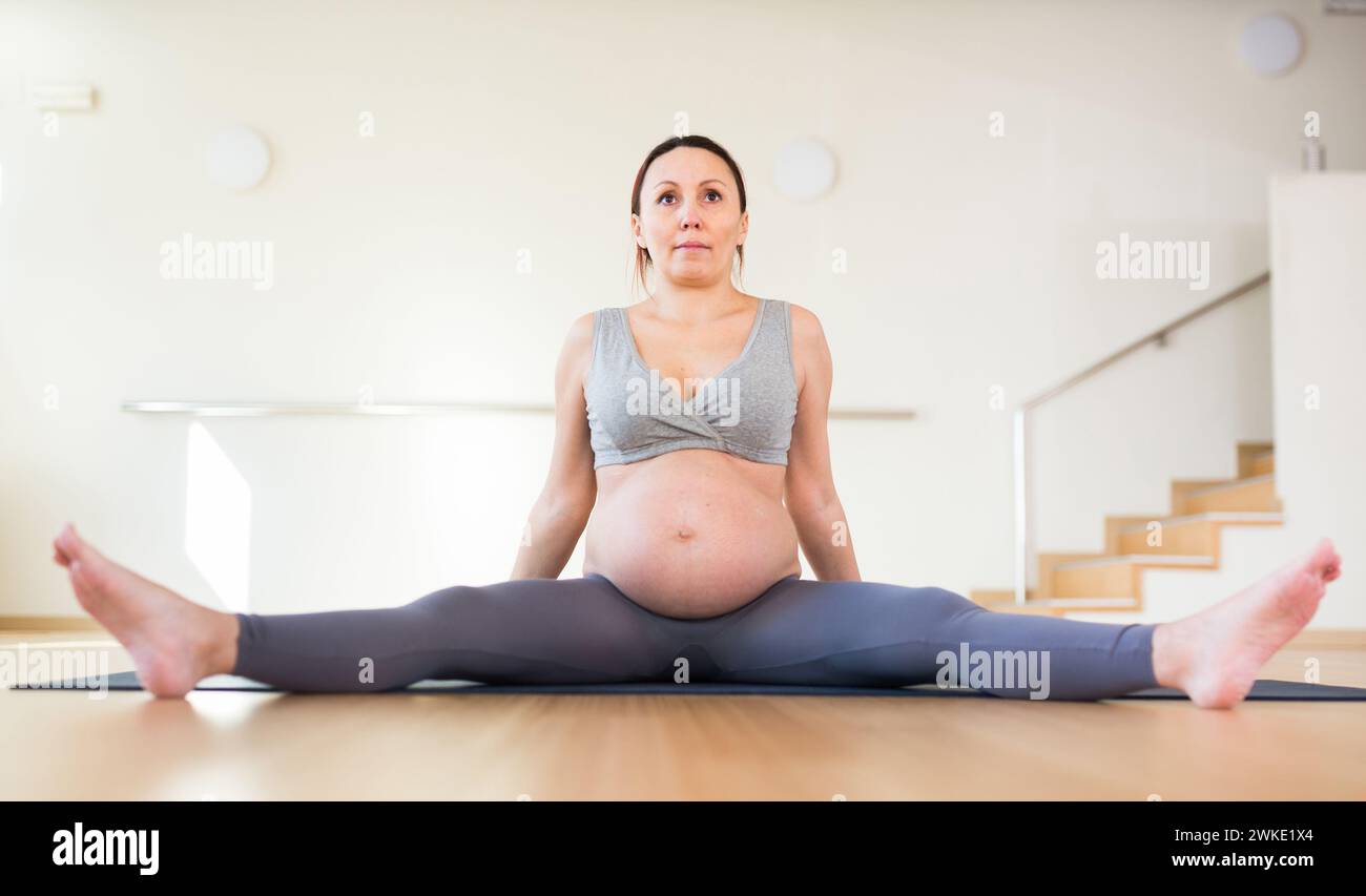 Pregnant woman is engaged in yoga. Seated Wide Legged Straddle or Upavistha Konasana Stock Photo