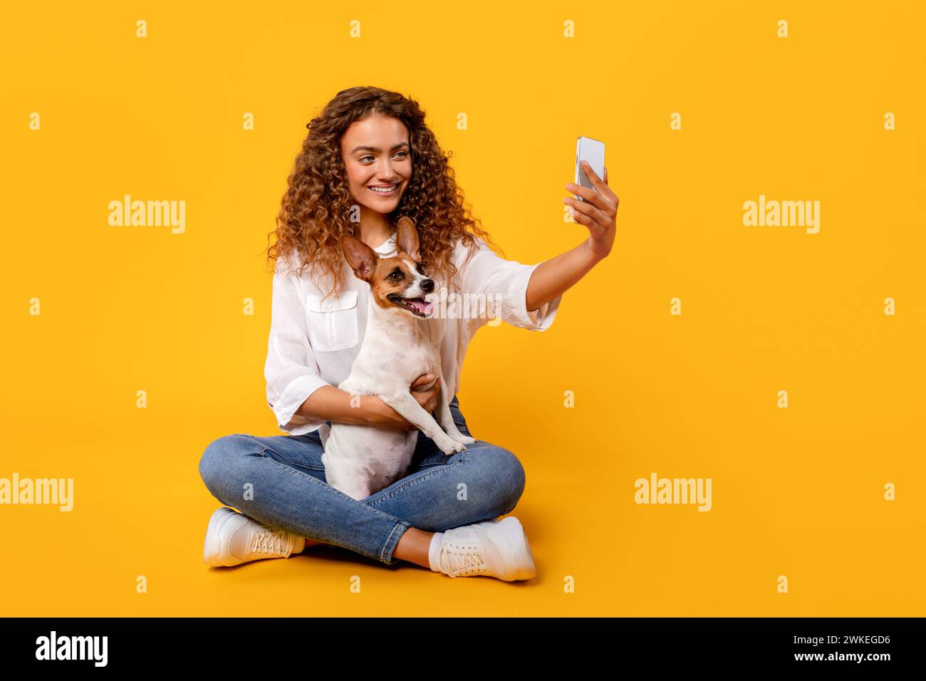 Curly-haired woman takes selfie with her joyful Jack Russell Stock Photo
