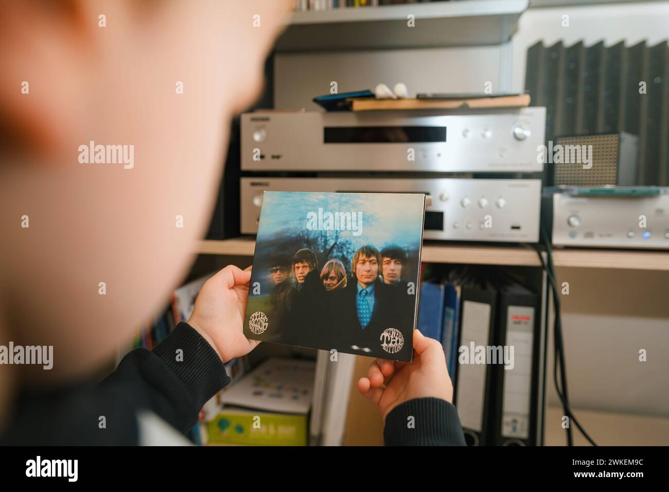 Paris, France - Jan 17, 2024: A luxurious scene where a toddler holds the SACD format of The Rolling Stones' Between the Buttons, with a high-end audio system in the background, depicting early exposure to music in an opulent setting. Stock Photo