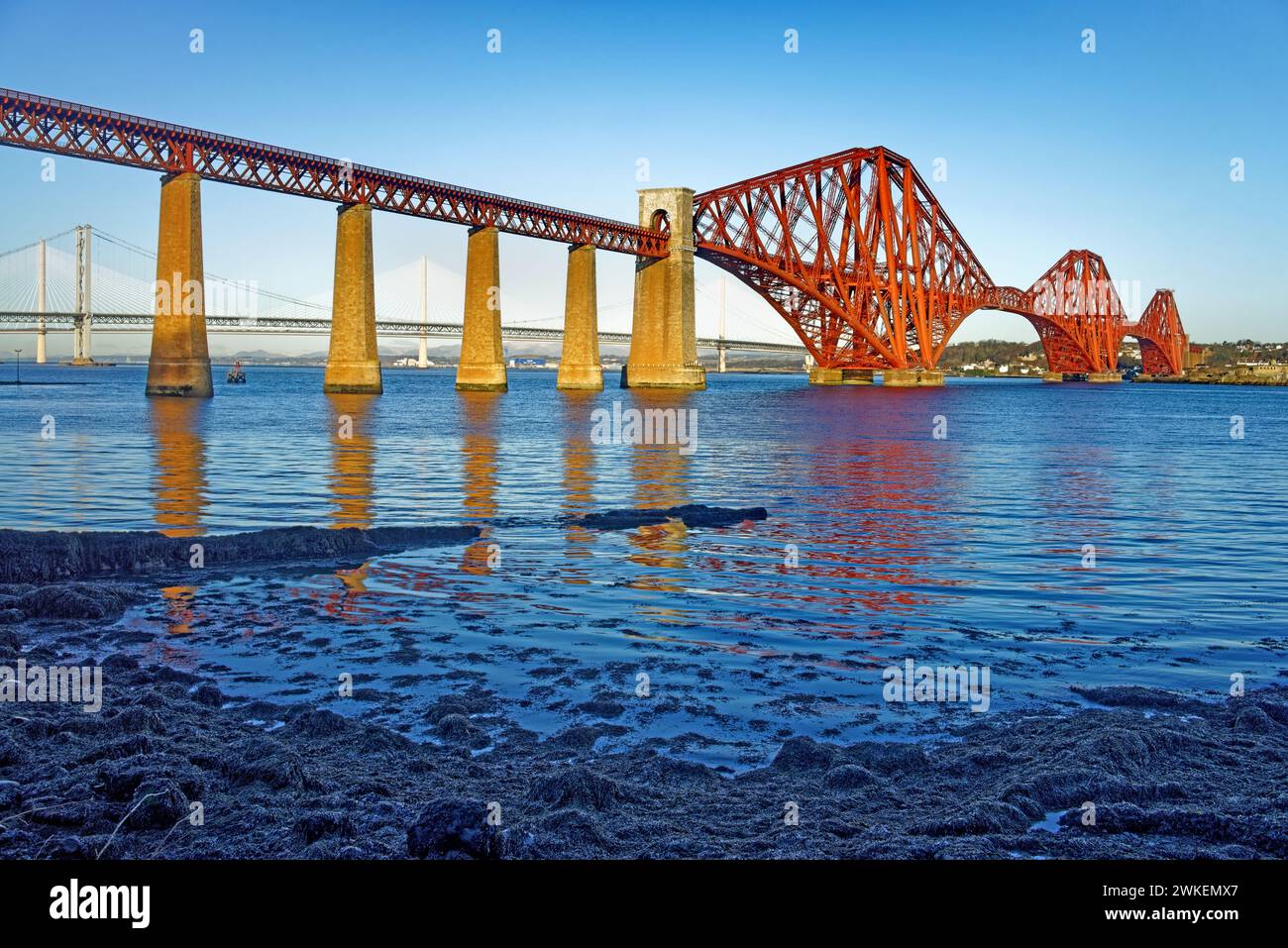 UK, Scotland, Forth Bridge crossing the Firth of Forth with Firth Road Bridge and Queensferry Crossing in the distance. Stock Photo