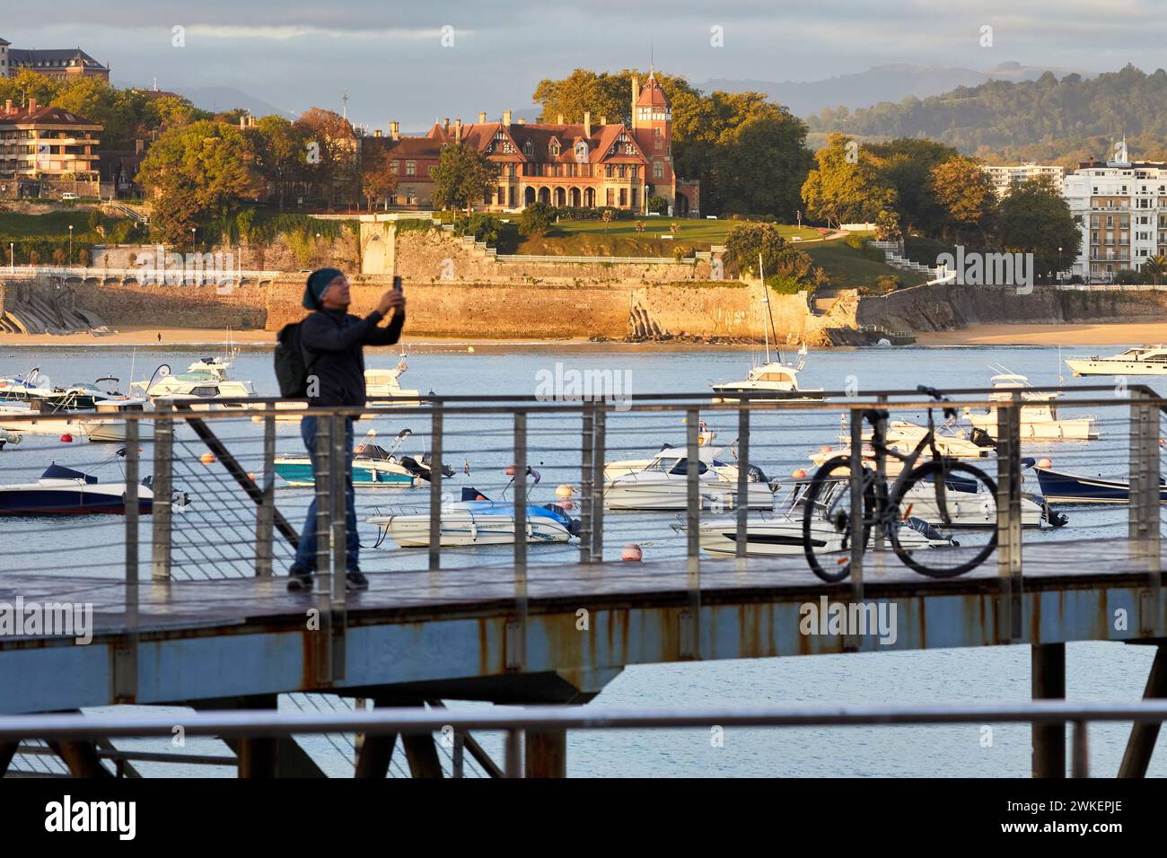 Tourist with a bicycle on the jetty of the Nautical Club, Puerto de Donostia, Bahia de La Concha, Miramar Palace, Donostia, San Sebastian, Basque Coun Stock Photo
