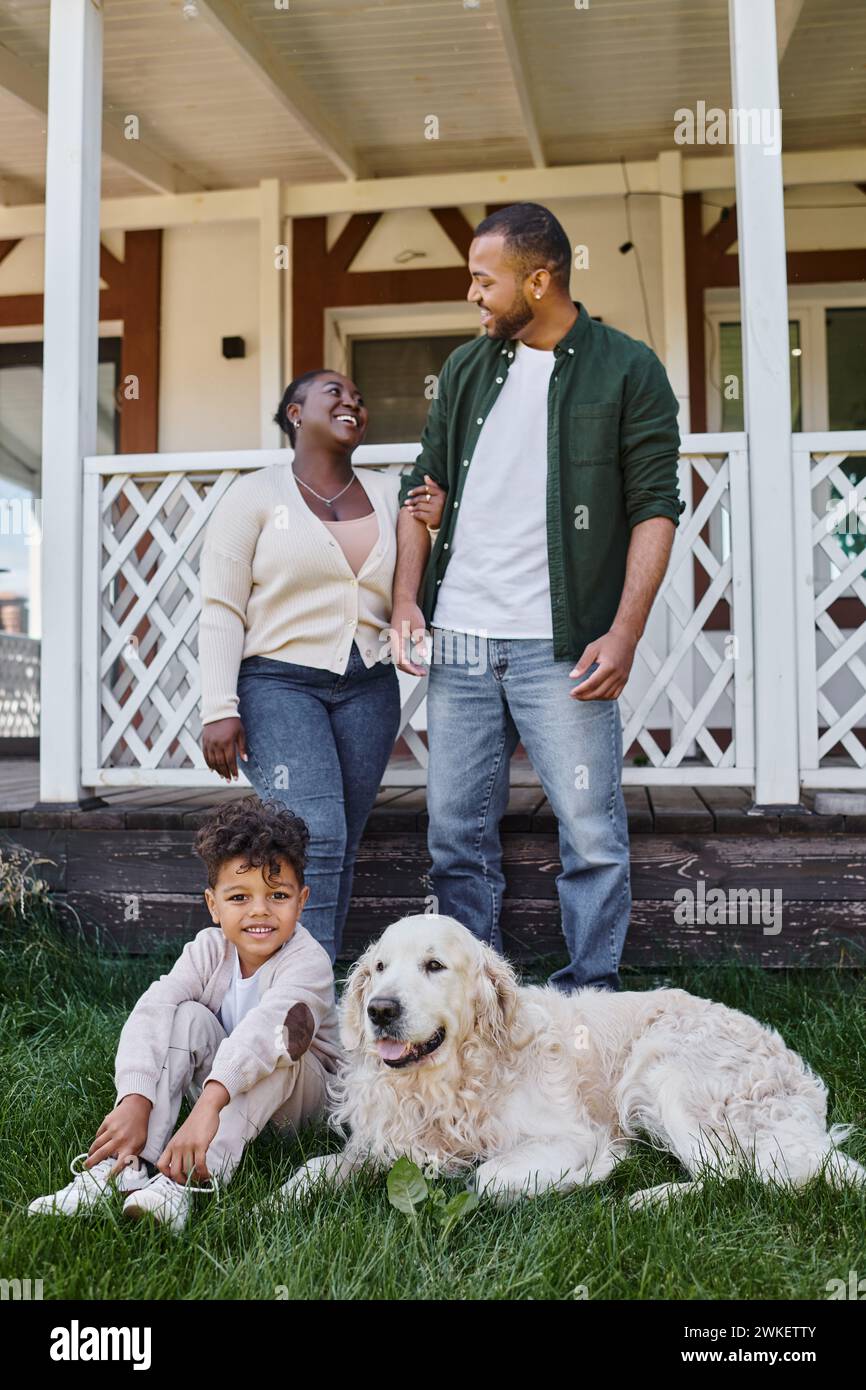 family moment, cheerful african american parents and son playing with dog on backyard of their house Stock Photo