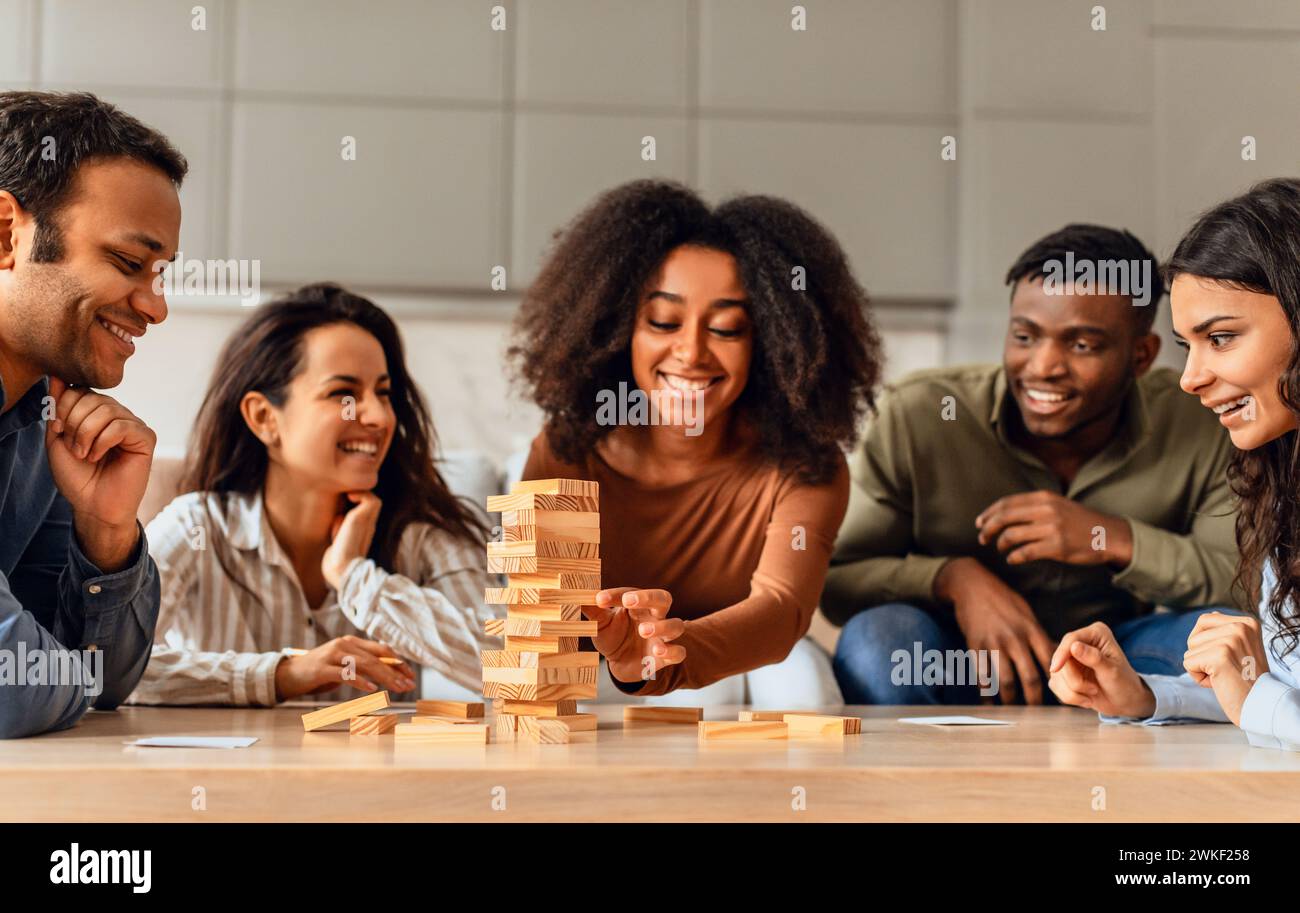 students group around table in kitchen engaging in board game Stock Photo