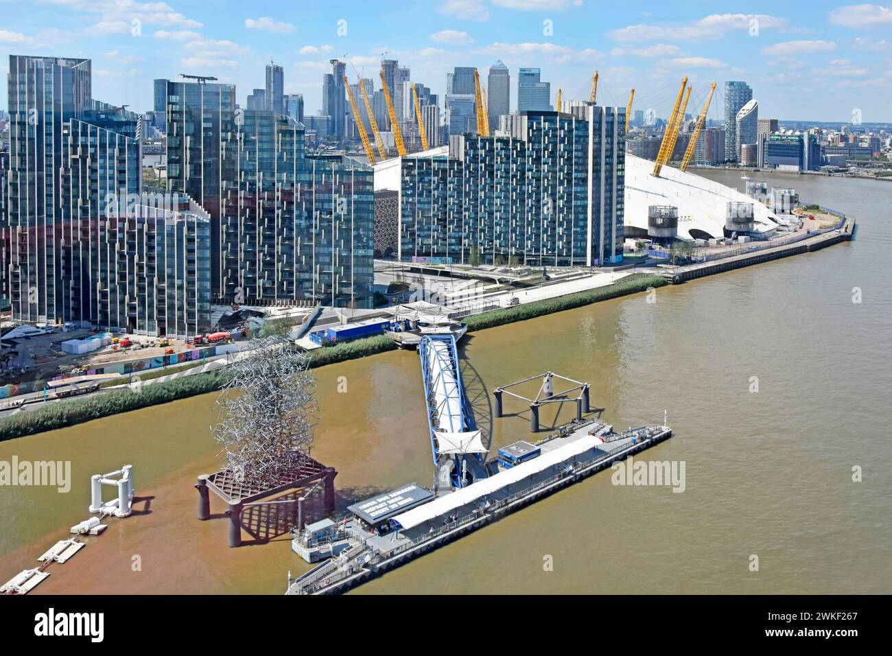Greenwich Pier Peninsular high tide River Thames modern high rise developments beside O2 arena roof Canary Wharf landmarks distant  London England UK Stock Photo