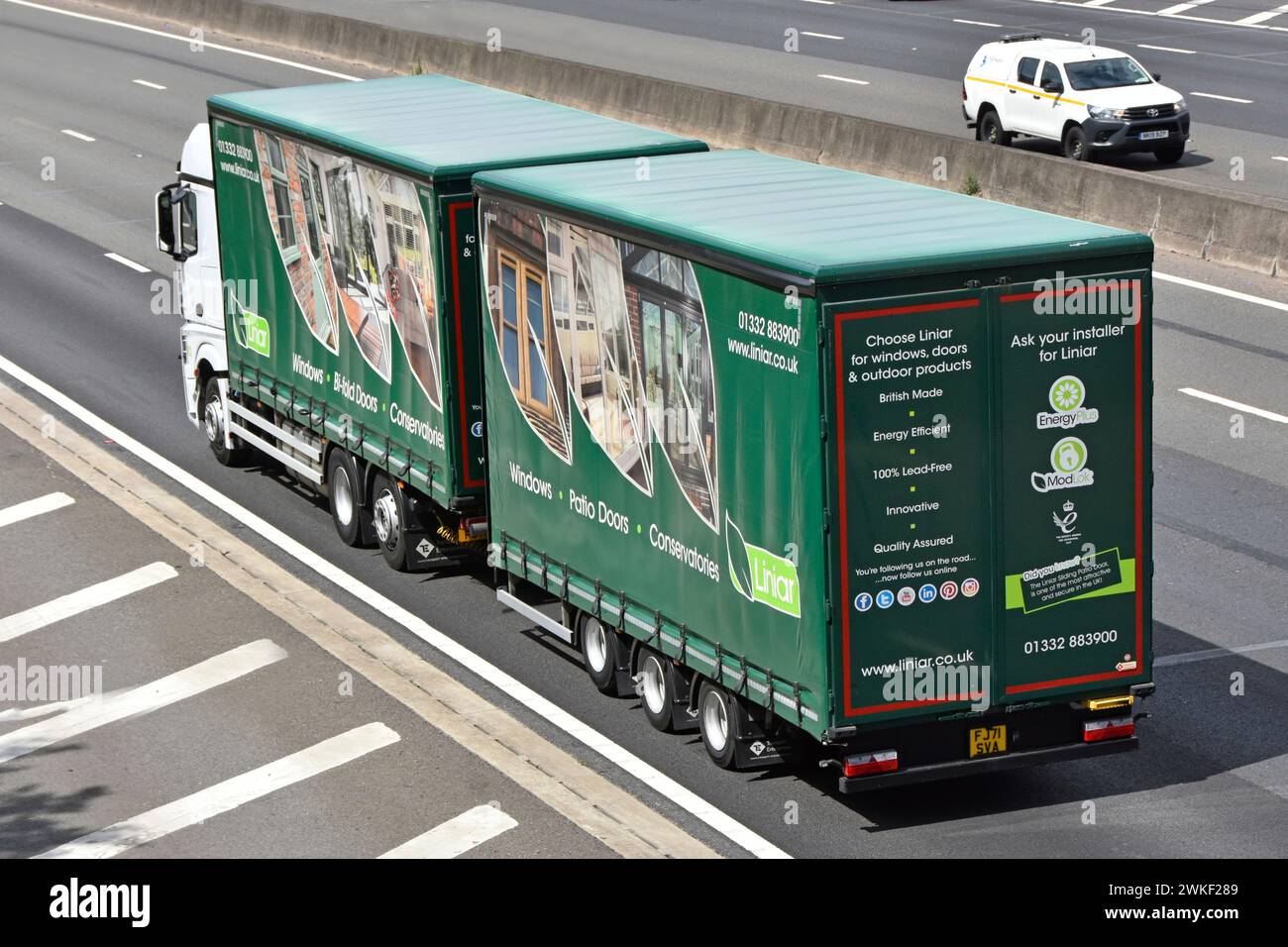 Curtain sided rigid hgv lorry truck & towed trailer combination Liniar uPVC business elaborate mobile product advertising graphics on M25 motorway UK Stock Photo