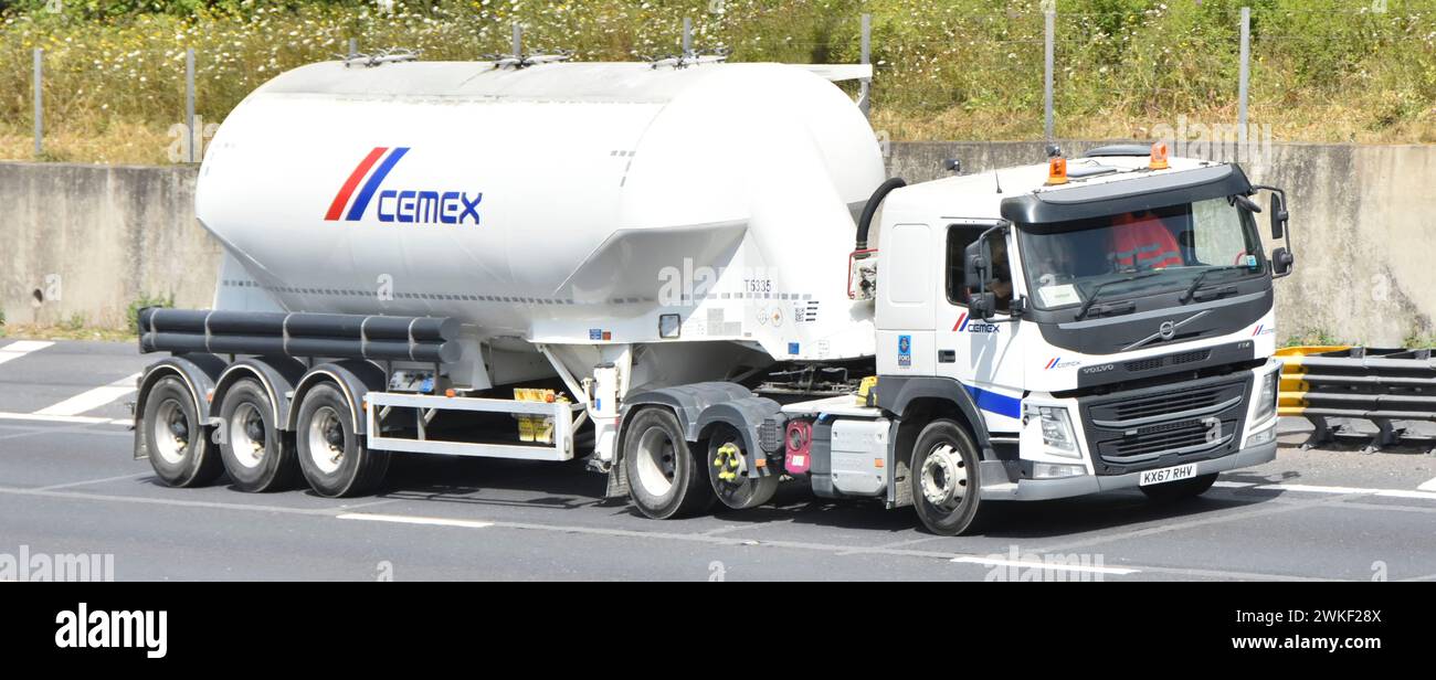 Cemex Cement white bulk dry powder semi trailer delivery tanker transporter & Volvo FM power unit raised economy axle driving M25 motorway England UK Stock Photo