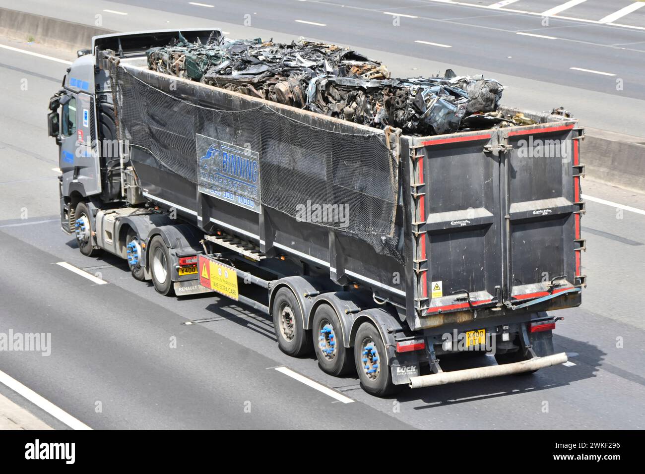 Renault hgv lorry in motion open top tipping semi trailer truck combination aerial side back rear view load of scrap metal on M25 motorway England UK Stock Photo