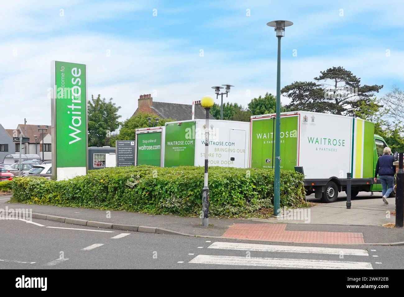 Waitrose supermarket store entrance sign parked delivery vans & customers car park shoppers pedestrian way in from street Billericay Essex England UK Stock Photo