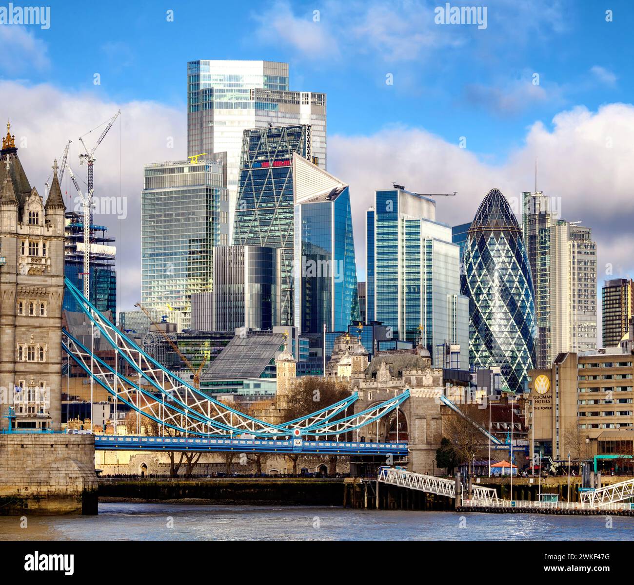 Buildings of the financial district of the City of London dwarfing the medieval Tower of London and Tower Bridge as it crosses the River Thames - UK Stock Photo