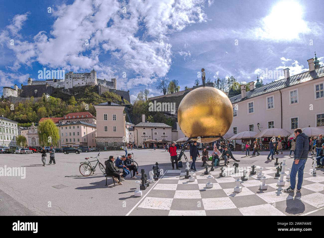SALZBURG, AUSTRIA - APRIL 27, 2023: Chess game drawn on asphalt in Kapitelplatz, near monument to Paul Fuerst 'Sphere', a golden ball. Stock Photo