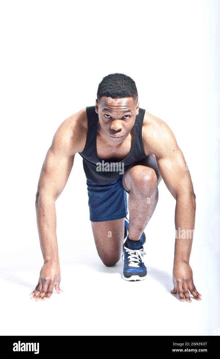 An athletic young black British man in a runners start position. Stock Photo