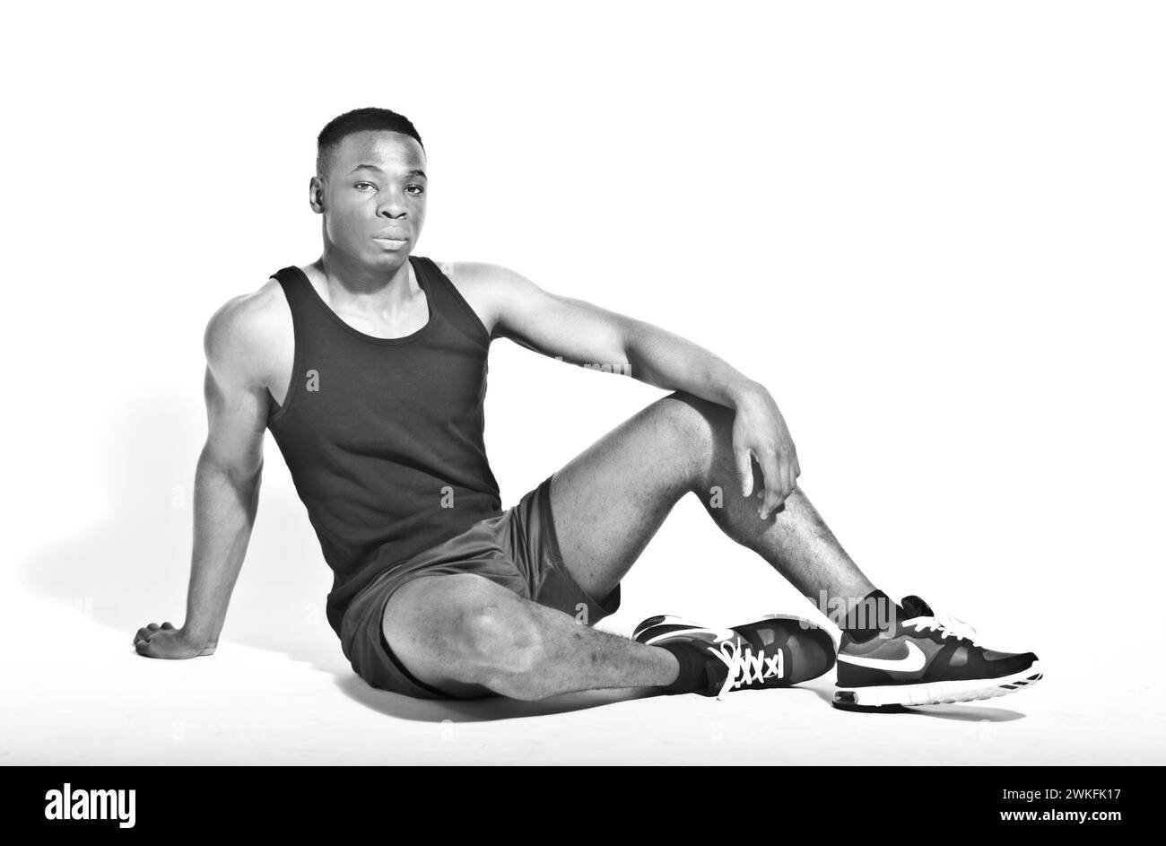 An athletic young black British man sitting down in a relaxed pose. Stock Photo