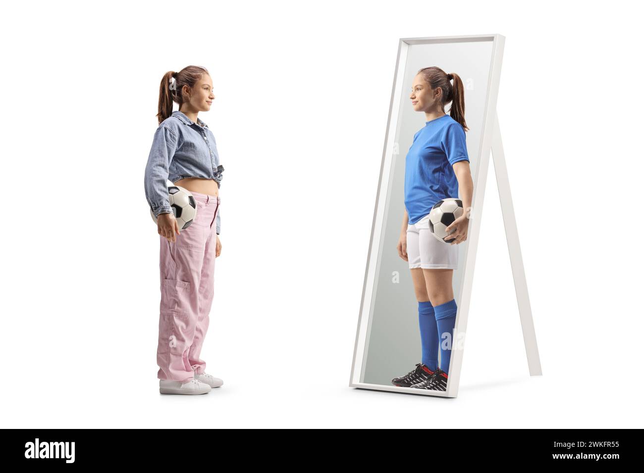 Full length shot of a girl holding a football and looking at a mirror at home Stock Photo