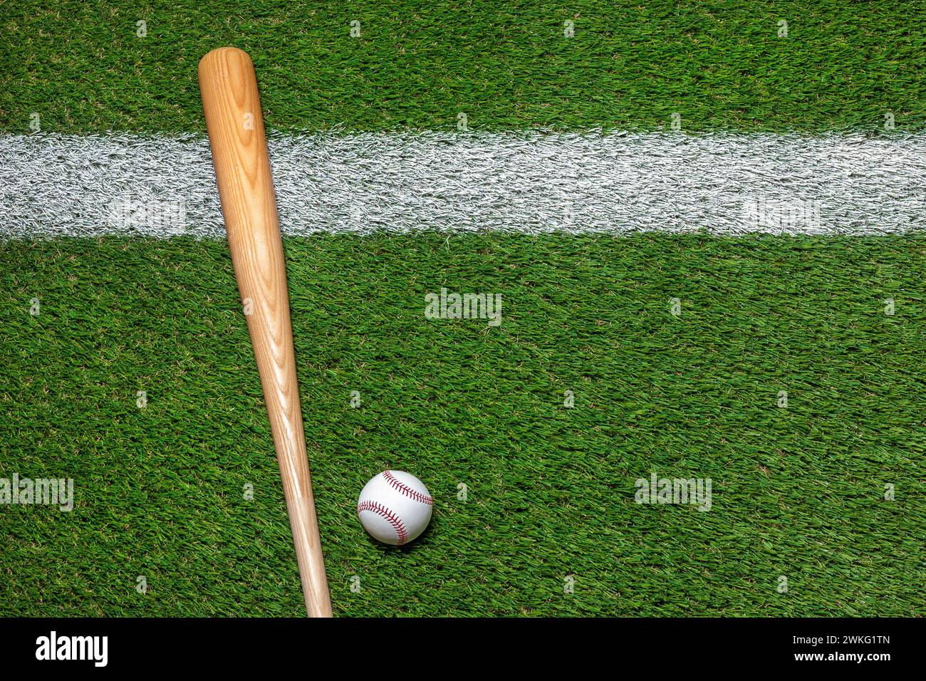 Baseball and wooden bat on grass field with white stripe overhead view Stock Photo