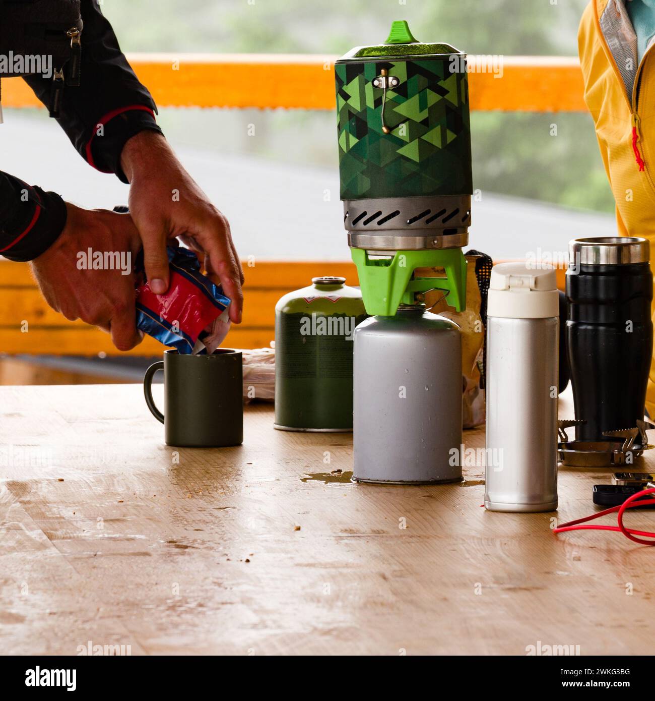 Tourists make coffee using gas cylinders in a tourist shelter on a wooden table. Stock Photo