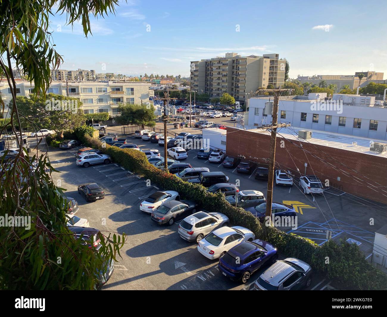 A bustling urban city parking lot surrounded by buildings under a clear blue sky Stock Photo