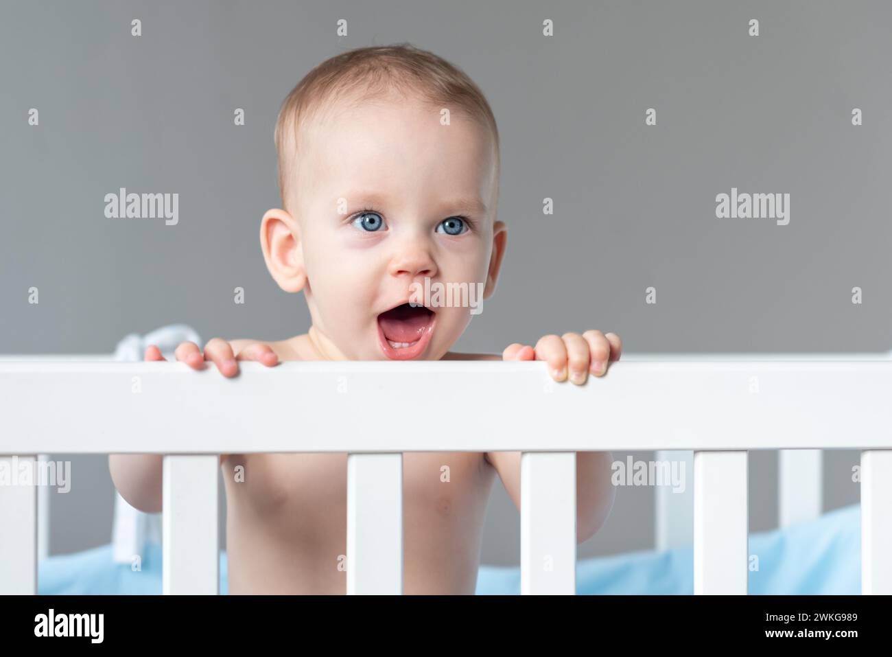 One year old baby standing in a crib smiling Stock Photo - Alamy