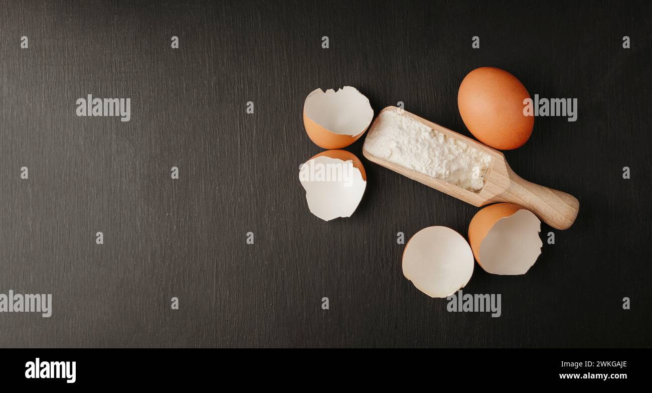Baking background with ingredients for making gingerbread : flour, eggs, kitchen tools, utensils and on dark wooden table. Top view. Flat lay style. M Stock Photo