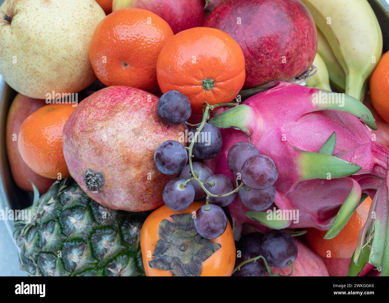 Variety of Fresh assorted fruits include Pineapple, Dragon fruit, Orange, Bananas, Black seedless grapes, Persimmon, pomegranate, apple and pear. Colo Stock Photo