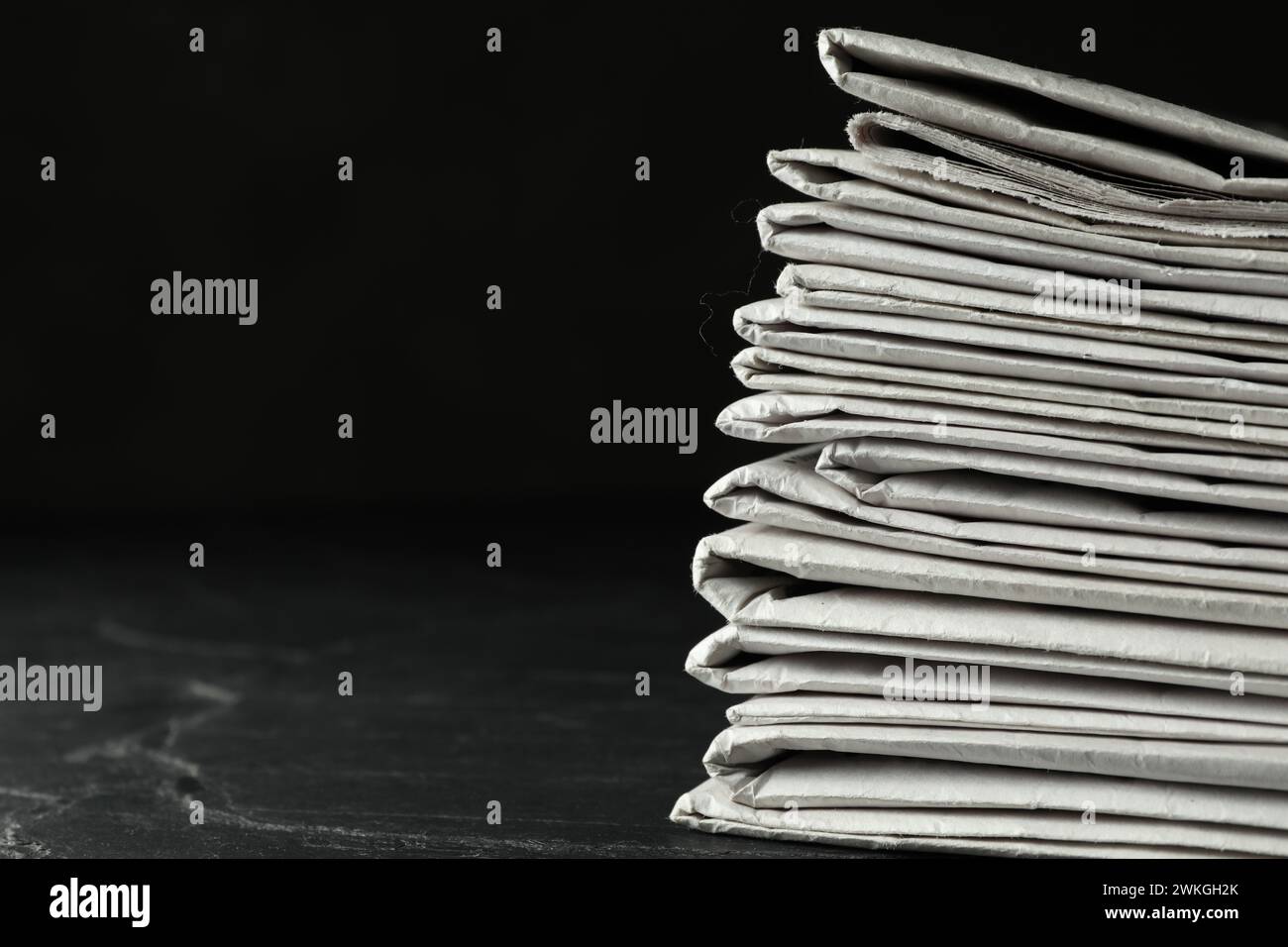Stack of newspapers on dark stone table, space for text. Journalist's work Stock Photo