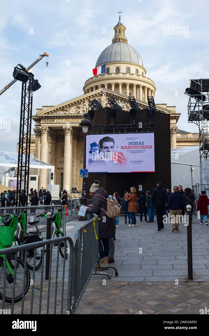Paris, France. 20th Feb 2024. Onlookers following the many preparations for the ceremony, in front of the portraits of Mélinée and Missak Manouchian Stock Photo