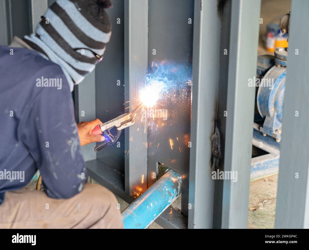 Welder man welding steel wall l, worker with unprotected and unsafety. Stock Photo