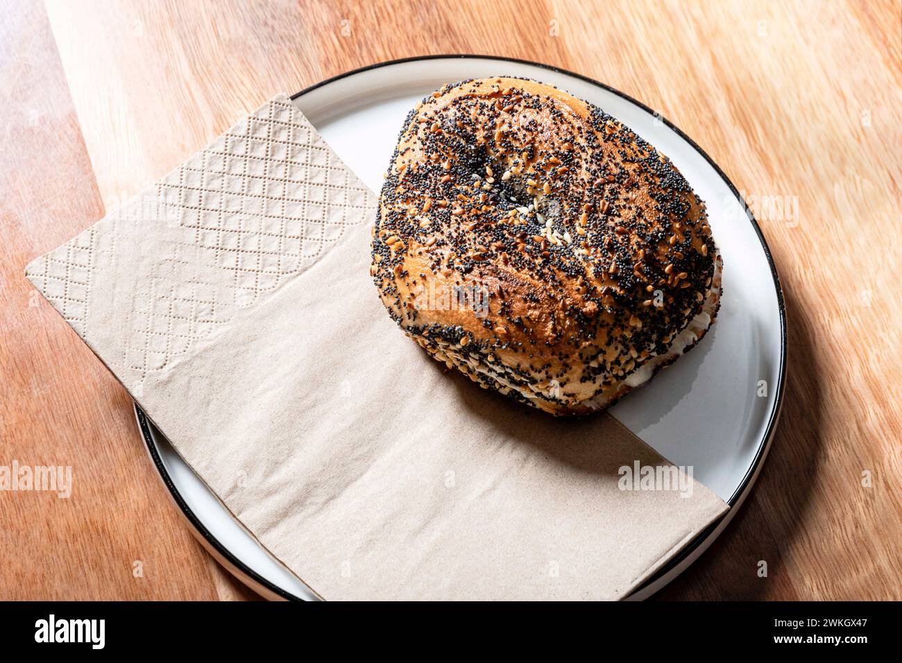 Sesame bagel sandwich on a plate, ready to be served in a cafe. Stock Photo