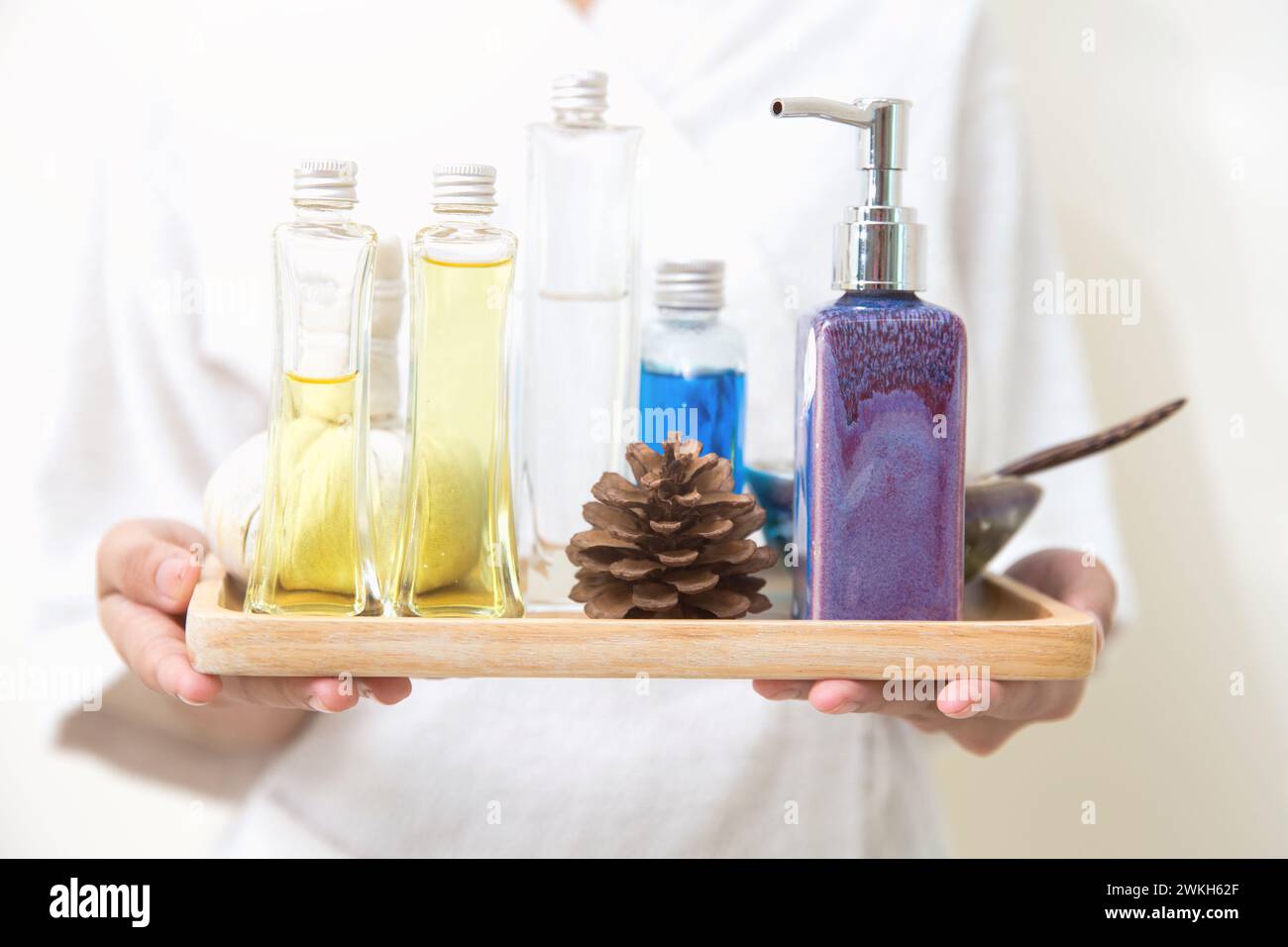 closeup masseur holding aroma herbal natural spa set oil cream wax body skin moisturizer treatment tray Stock Photo