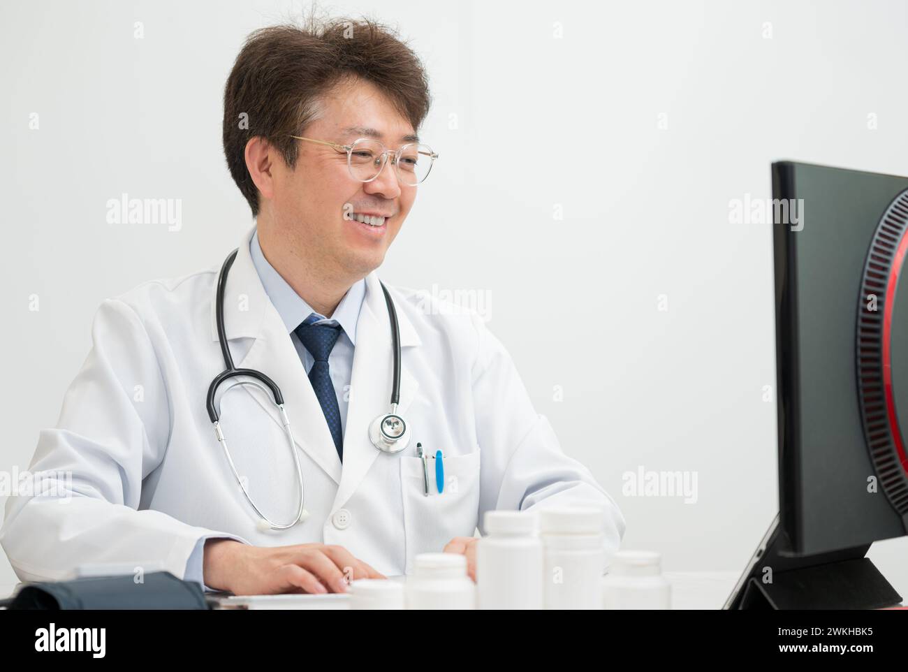 A middle-aged male doctor performing telemedicine using a computer Stock Photo