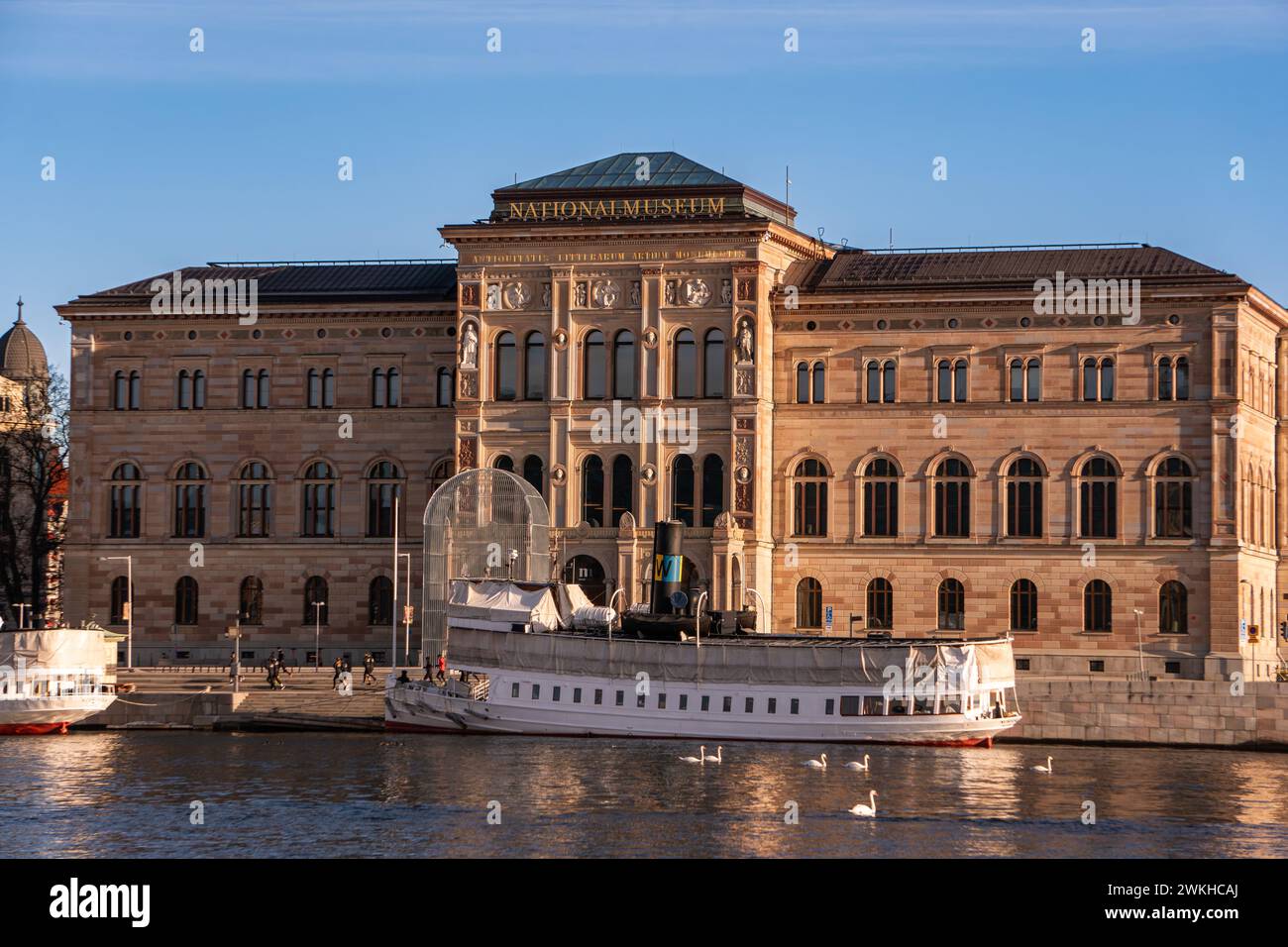 The national museum of Sweden, Stockholm. Bright sunlight, blue sky, passenger ferry, swans, a waterway and winter. Stock Photo