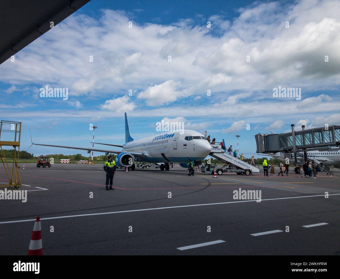 Kaliningrad, Russia - October 12, 2023: Travelers ascending stairs to board an airplane on tarmac with clear skies and airport crew in attendance. Stock Photo