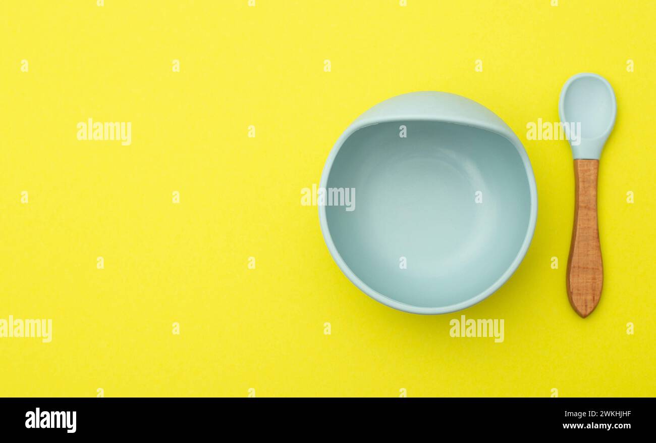 Silicone baby plate and spoon on a yellow background. The concept of