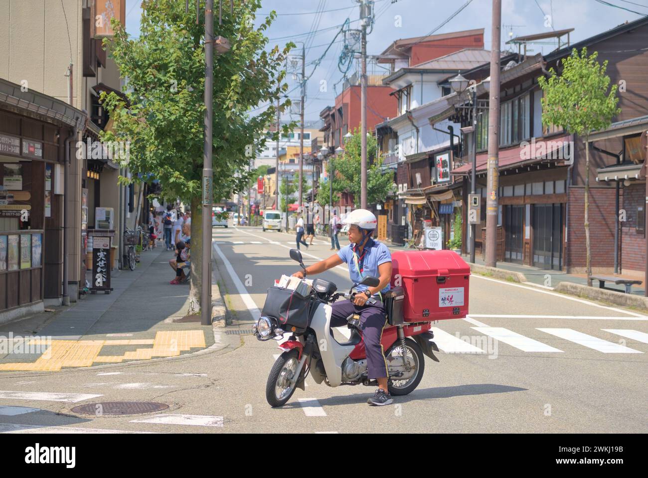Japanese postman on a motorcycle in the streets of Takayama on a sunny summer day. Japan, Takayama, 08 29 2019. Stock Photo