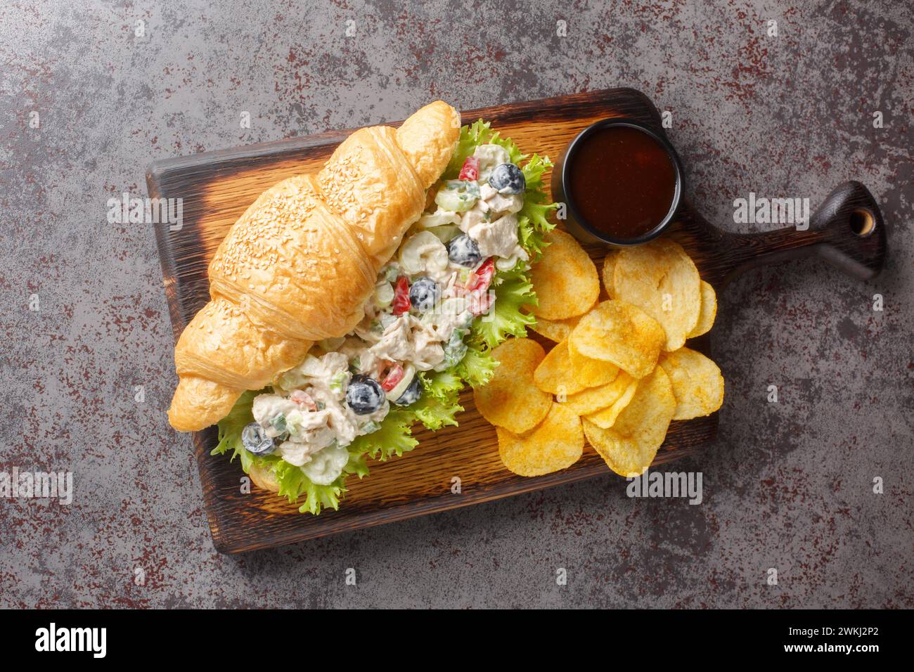 Homemade Healthy Chicken Salad Croissant Sandwich with potato chips closeup on a wooden board on the table. Horizontal top view from above Stock Photo