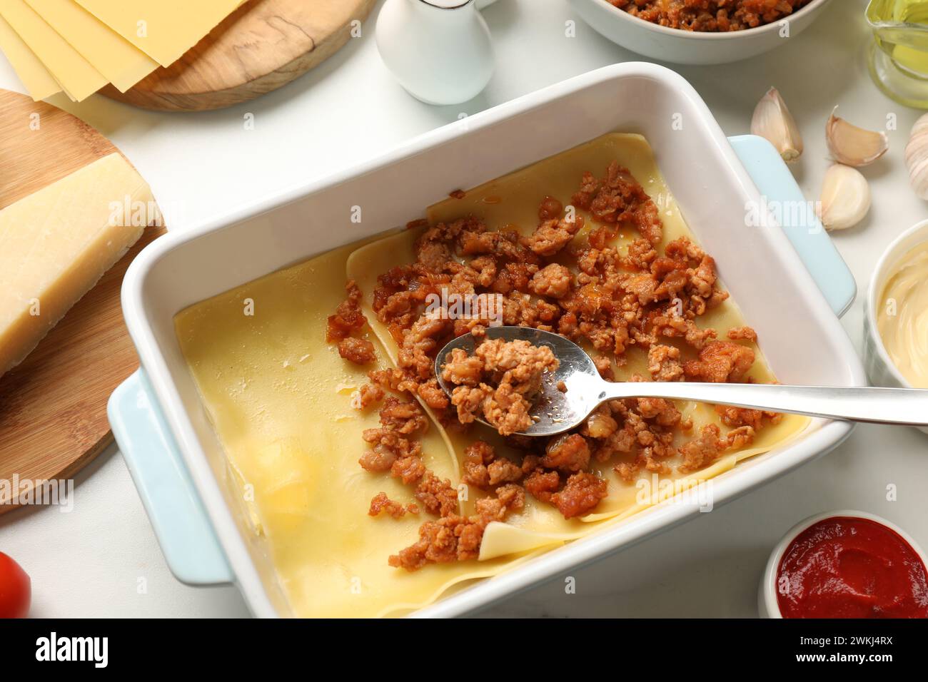 Cooking lasagna. Pasta sheets and minced meat in baking tray on white table, above view Stock Photo