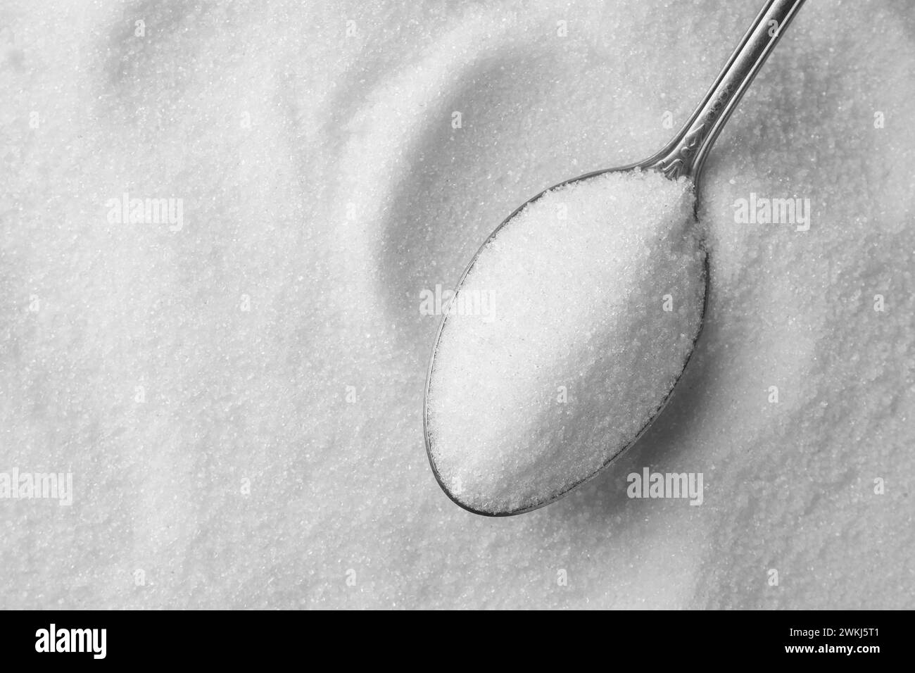 Metal spoon on granulated sugar, top view Stock Photo