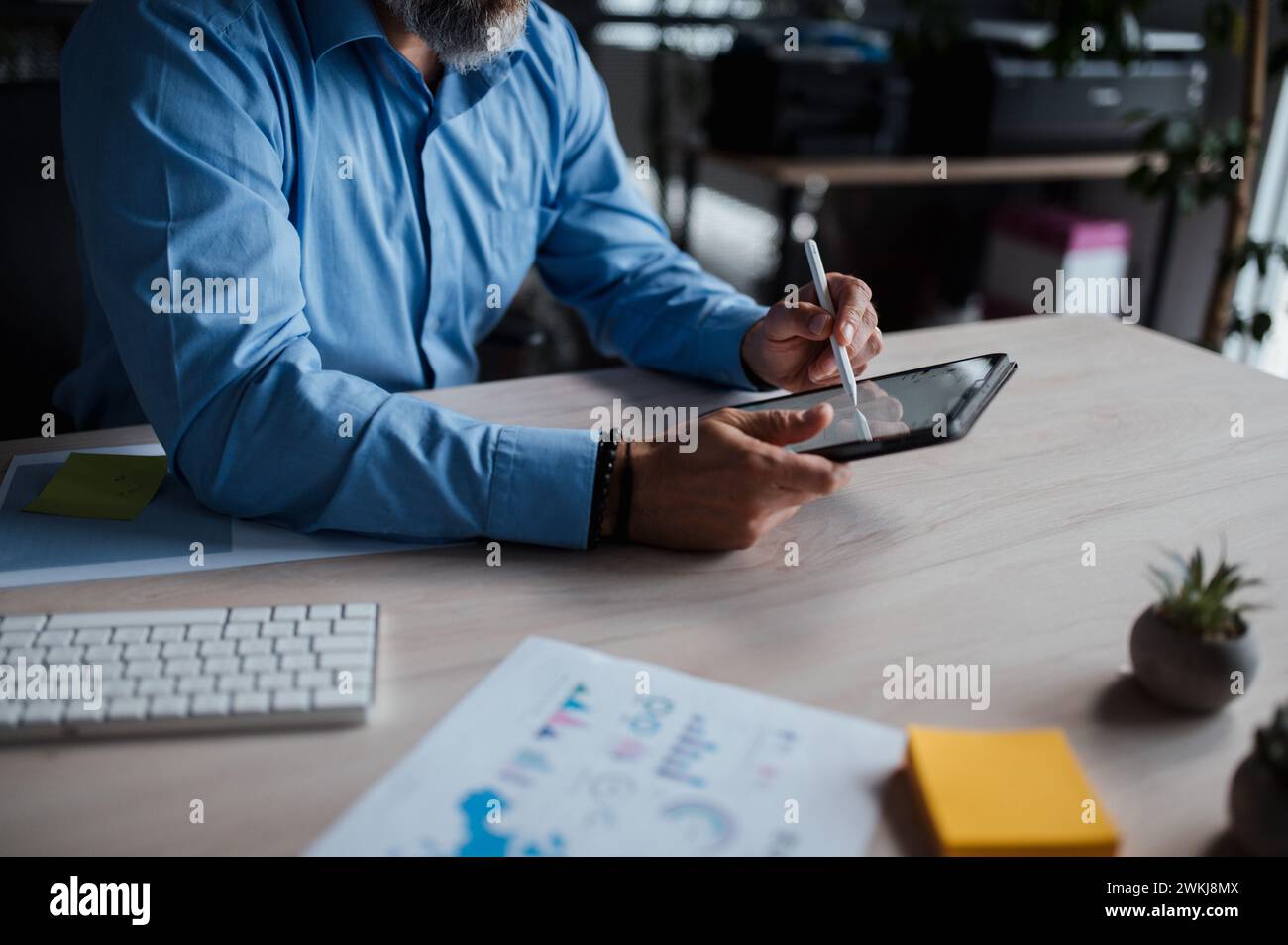 Man is sitting at a desk using a tablet computer Stock Photo