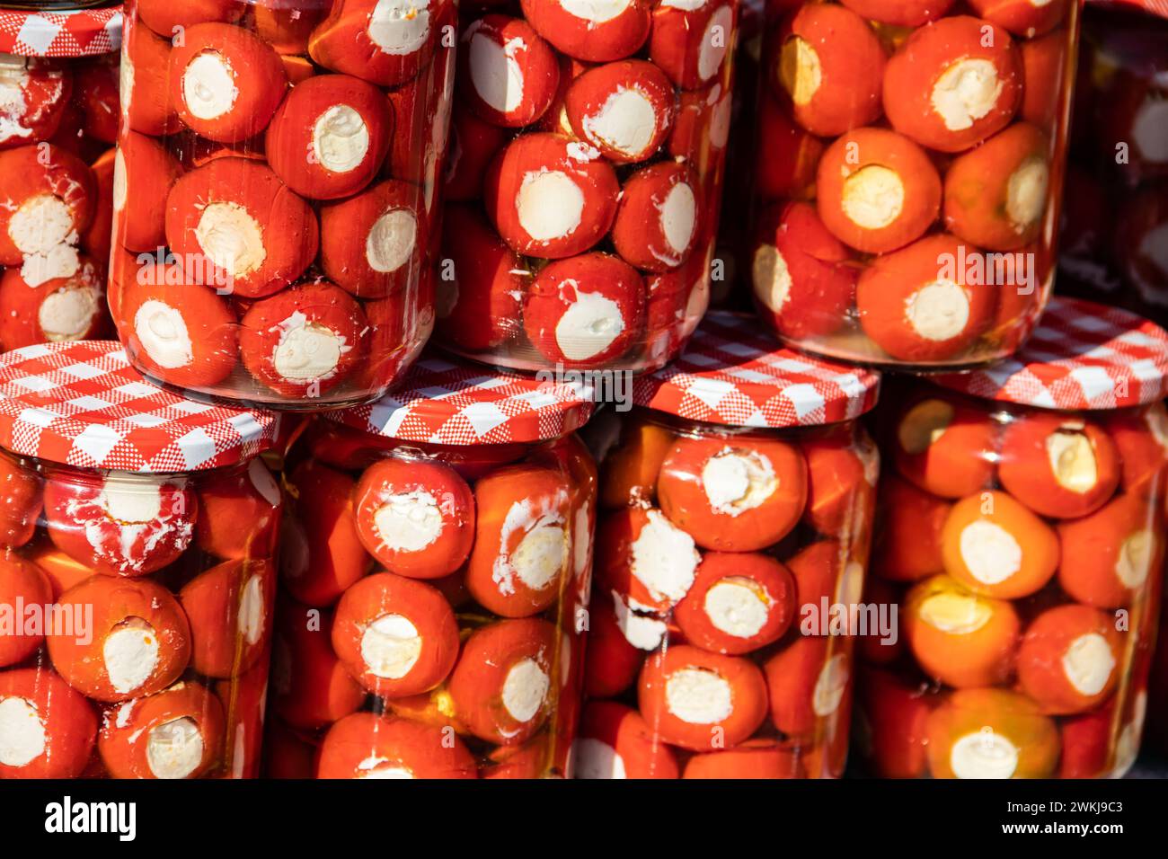 Homemade canned vegetables in cans, pickled small cherry tomatoes stuffed with cheese and onion, in a rural style of Serbian country side Stock Photo