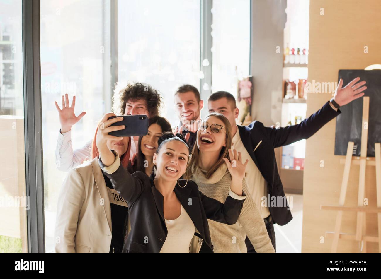 A group of young business colleagues posing together and taking a self-portrait with a smartphone. Friends with happy smiling face expressions. Stock Photo