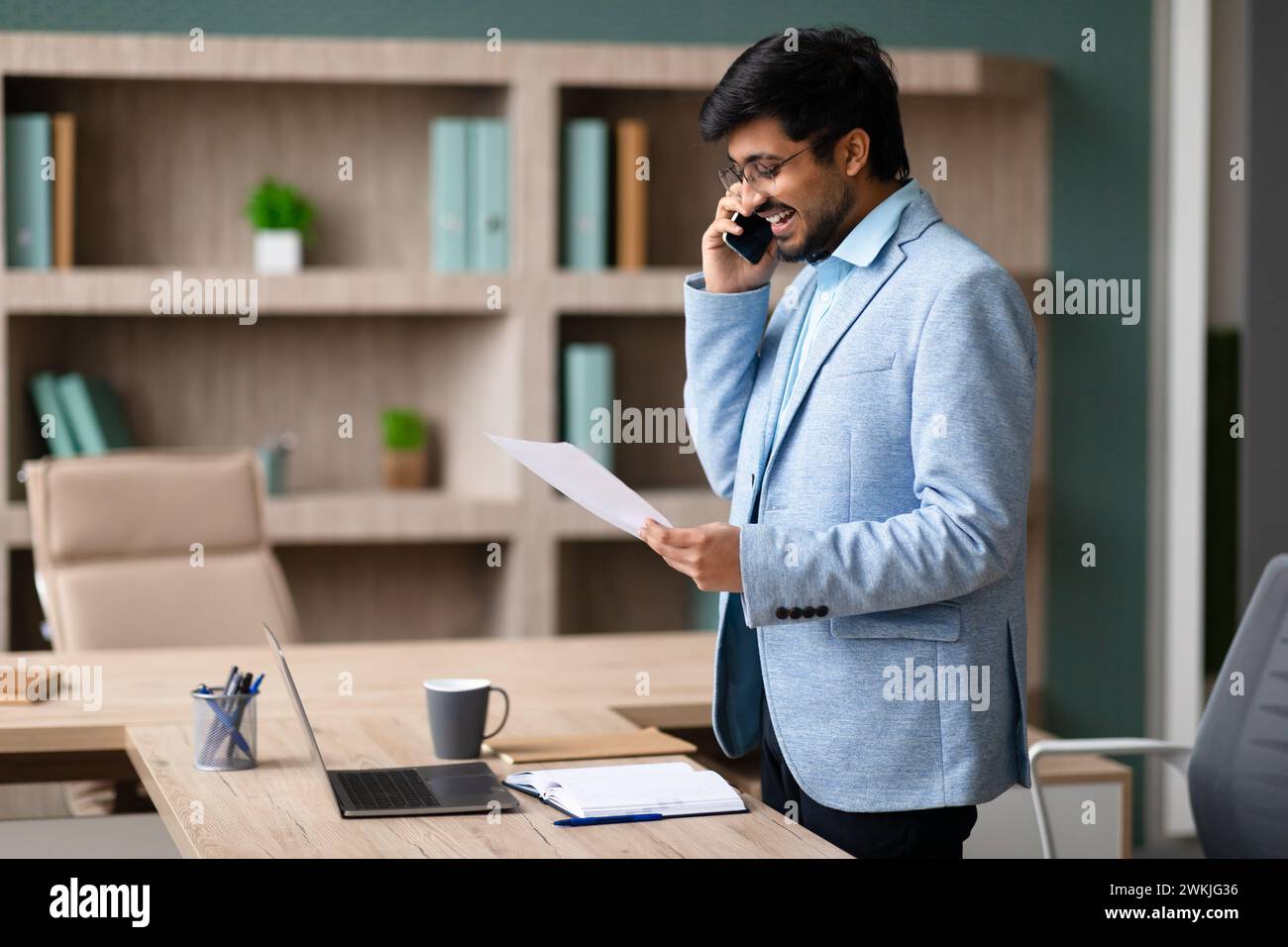 Indian Businessman Discussing Documents Over the Phone In Office Stock Photo