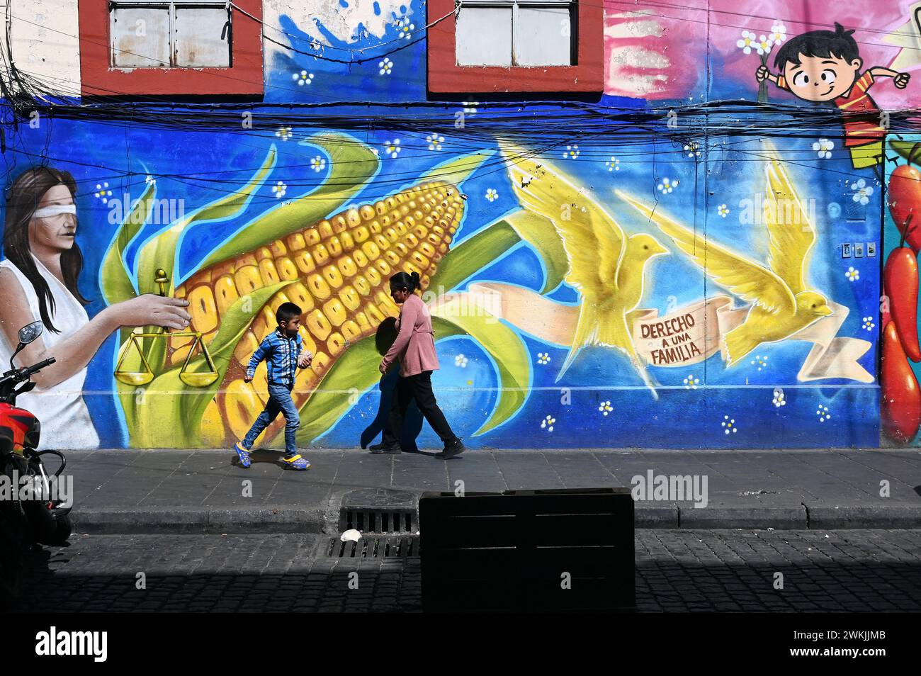 Passers-by in front of a mural with a corn cob in the historical centre, Mexico City Stock Photo